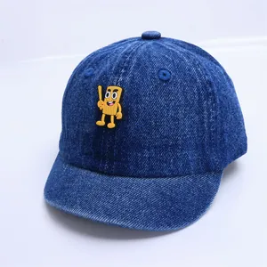 Détail de la casquette en denim bleu foncé avec un patch en PVC de dessin animé jaune
