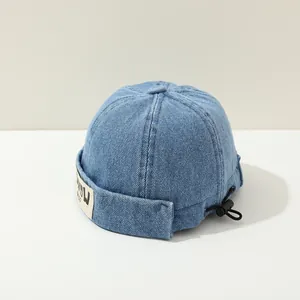Detail of blue denim skull cap featuring a sewn fabric label and adjustable back cord