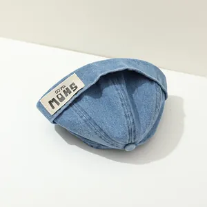 Detail of blue denim docker cap featuring white brand label and premium fabric texture