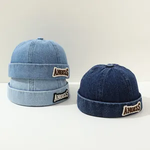 Detailed view of three denim docker caps in light, medium, and dark blue with letter embroidery