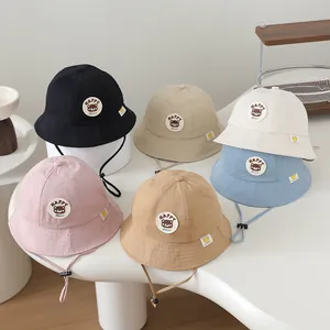Detail view of cotton bucket hats for toddlers in six colors with happy bear patches