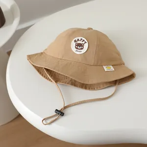 Detail of khaki children's sun hat featuring Happy Bear embroidery and adjustable wind rope