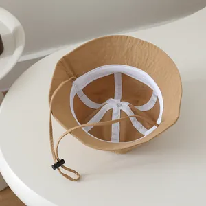 Detail of khaki fisherman hat featuring white sweatband and adjustable windproof strap