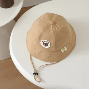 Detail of khaki cotton baby sun hat with plush happy bear patch and adjustable chin strap