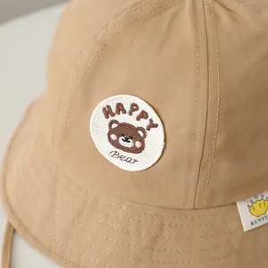 Close-up of embroidered bear and Happy Bear text on a khaki cotton kids sun hat