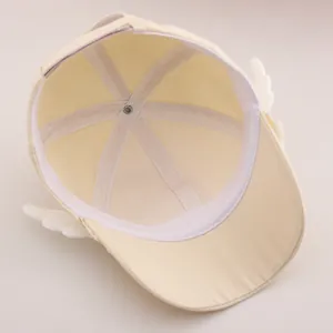 Détail intérieur d'une casquette enfant beige avec bandeau et petites ailes en peluche