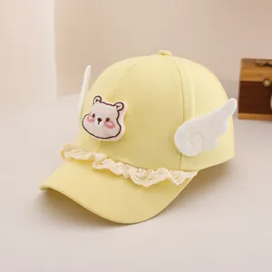 Détail d'un chapeau de soleil pour bébé avec ours brodé, ailes en peluche et dentelle