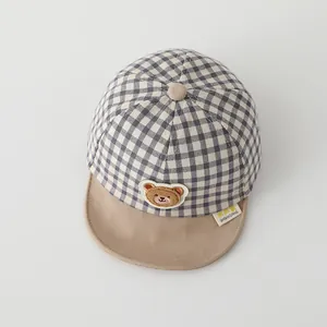 Macro detail of toddler plaid baseball cap featuring a plush bear and soft khaki brim