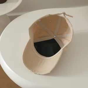 Détail de la casquette en coton kaki avec boucle réglable et étiquette smiley jaune