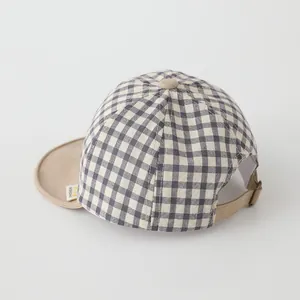 Close-up of baby plaid baseball cap showing black white check fabric and metal buckle