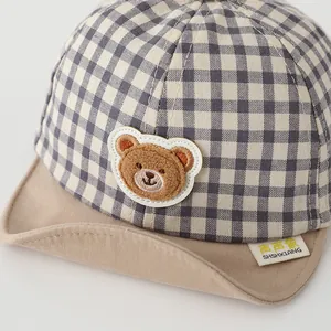 Detail of baby baseball cap featuring grey plaid fabric and 3D plush bear patch