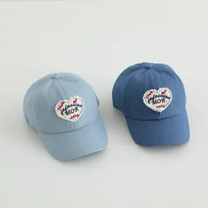Close-up of denim baby baseball caps with heart patch and Fashion MOA embroidery
