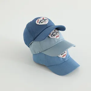 Close-up of heart patch denim caps in dark, medium and light blue vintage washes