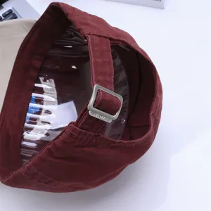 Detail view of adjustable metal buckle on dark burgundy cotton baseball cap with strap