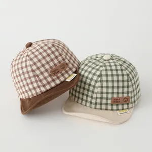 Detail of brown and green plaid baby baseball caps with bear leather patch and soft brim