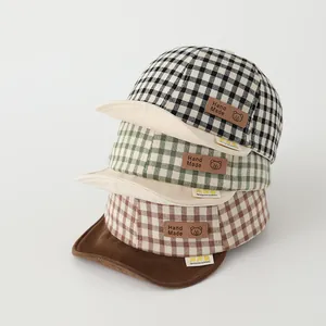 Detail of infant soft-brim baseball caps with plaid patterns and cute bear leather patches