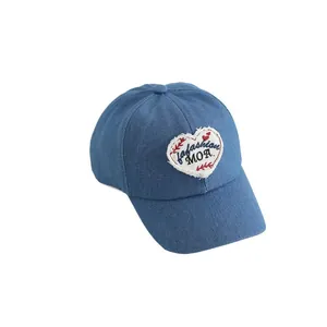 Denim kids baseball cap with a white heart patch and embroidery on a white background