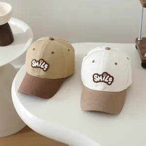 Detail of children's baseball caps with SMILE embroidery patch in khaki and white