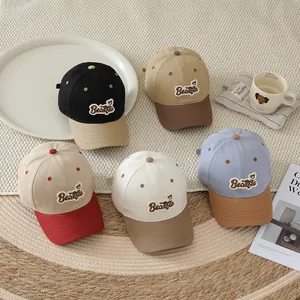 Detailed close-up of colorful children's baseball caps with bear embroidery on a cozy rug