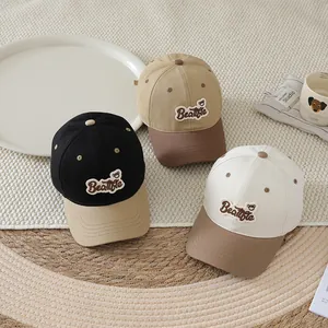 Three kids' cotton baseball caps with bear embroidery and curved brims in neutral colors