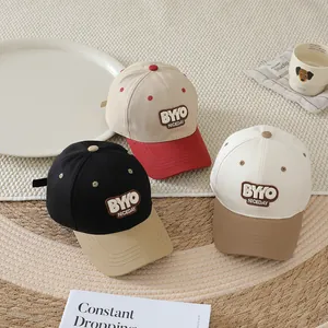 Detailed view of three stylish kids' baseball caps with contrast brims and letter patches