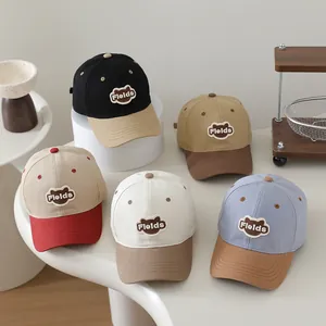 Detail of five multi-colored kids' baseball caps with embroidered bear patch on a stand