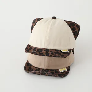 Detail of stacked cotton baby baseball caps featuring leopard print ears and brim design