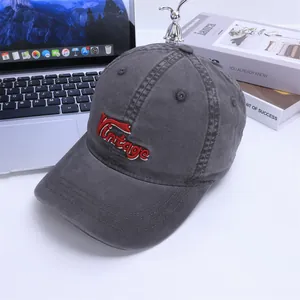 Detail view of dark gray vintage baseball cap with red 3D embroidery and washed cotton texture