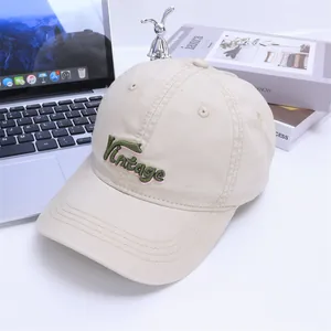 Detail of vintage letter embroidery on beige canvas kids baseball cap with curved brim
