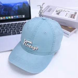 Detail of light blue cotton baseball cap with vintage embroidery on a white desk