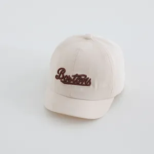 Detalle del bordado Boston en una gorra de béisbol de lona beige con textura fina