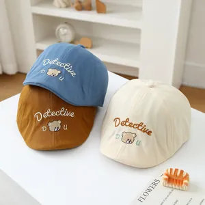 Detailed close-up of retro cotton baby berets in blue, tan, and cream with bear embroidery
