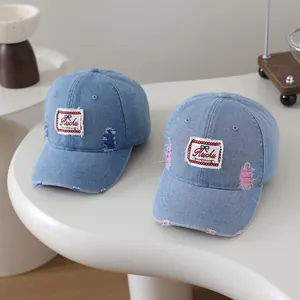 Detail of distressed denim baseball caps showing frayed holes and Ruchu patches