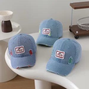 Detail of vintage distressed denim baseball caps with colorful patches on a white table