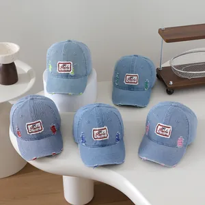 Detail shot of distressed denim kids baseball caps with vintage patches and colored stitching