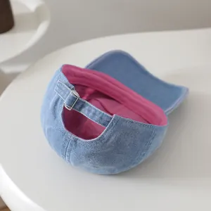 Detail view of denim baseball cap with pink lining and adjustable metal buckle