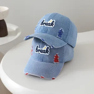 Detail of washed denim baseball caps with distressed holes and break letter embroidery