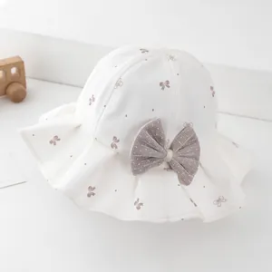Close-up of white sun hat with brown bows and a large grey mesh ribbon detail