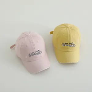 Kids vintage baseball caps in pink and yellow with 'NICE DAY' embroidery and distressed detail