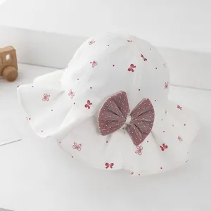 Detail of white baby sun hat with red bow and dots pattern on clean white background