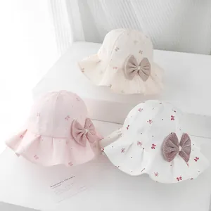 Detail of baby sun hat with floral pattern and large decorative bow on white steps