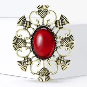 Broche badge chardon vintage dorée avec une grande gemme rouge et motifs géométriques creux