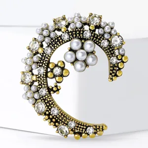 Vintage gold moon brooch with pearls and crystals on a clean white display stand