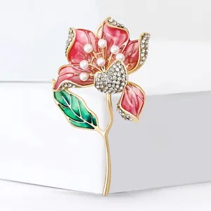 Spilla a ibisco dorata con petali in smalto, perle bianche e strass scintillanti