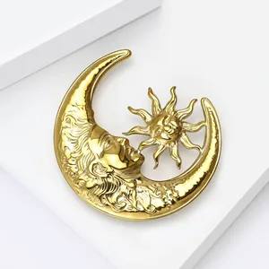 Detail of a celestial gold metal moon and sun brooch with liquid metal texture finish