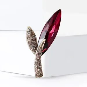 Elegant gold leaf brooch featuring a large red faceted crystal and champagne diamonds