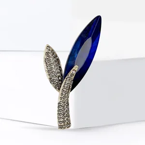 Elegant leaf brooch with deep blue crystal and white rhinestones on a gold metal base