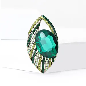 Elegant eye-shaped brooch with green crystal and sparkling rhinestones on gold metal
