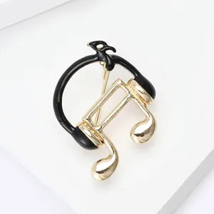 Macro d'une broche note de musique et casque élégante dorée et noire en alliage de zinc