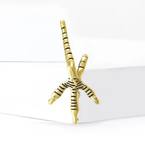 Broche griffes d'aigle dorées avec rayures noires texturées sur un support blanc